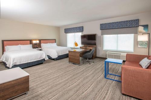 RichwoodにあるHampton Inn Richwood Cincinnati South, KYのベッド2台とソファが備わるホテルルームです。