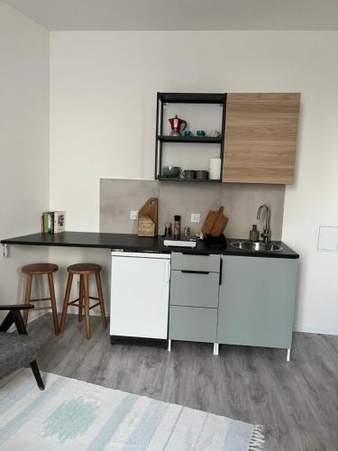 a kitchen with a sink and a counter with stools at Apartament Wierzbięcice 44 in Poznań