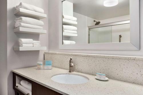 uma casa de banho com lavatório, espelho e toalhas em Hampton Inn Waycross em Waycross