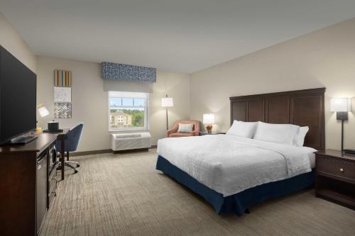 オーガスタにあるHampton Inn Augustaのベッドとテレビが備わるホテルルームです。
