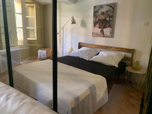 a bedroom with a bed with white sheets and a mirror at Logement avec deux velos in Hyères