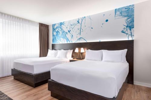 2 camas en una habitación de hotel con sábanas blancas en Holman Riverfront Park Hotel Salem, Tapestry By Hilton, en Salem