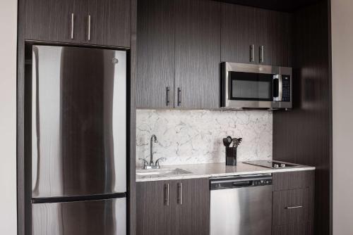 a kitchen with a stainless steel refrigerator and a microwave at Holman Riverfront Park Hotel Salem, Tapestry By Hilton in Salem