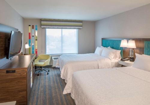 a hotel room with two beds and a flat screen tv at Hampton Inn Columbus in Columbus