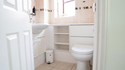 a bathroom with a toilet and a sink and a window at The Cosy Corner in Loughton