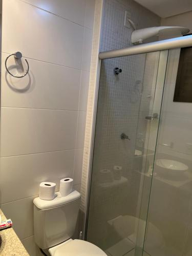 uma casa de banho com um WC e uma cabina de duche em vidro. em Flat Espetacular no Flamboyant em Goiânia