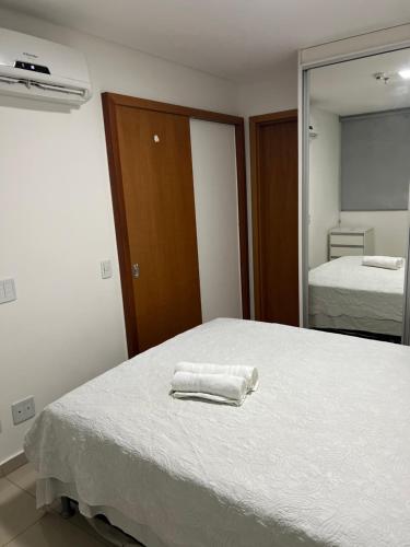 a bedroom with a bed with two towels on it at Flat Espetacular no Flamboyant in Goiânia
