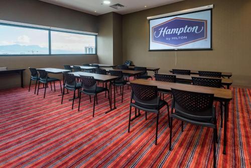 a conference room with tables and chairs and a projection screen at Hampton By Hilton Bogota Airport in Bogotá