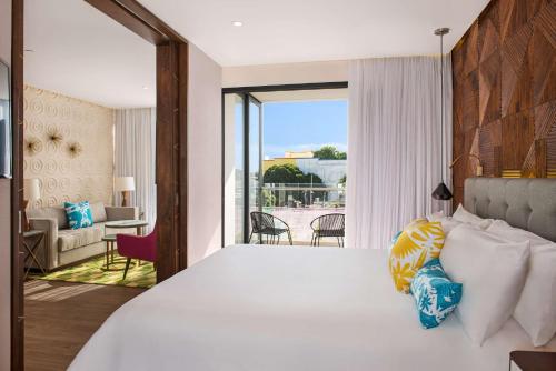 a bedroom with a large bed with a view of a living room at The Fives Downtown Hotel & Residences, Curio Collection by Hilton in Playa del Carmen