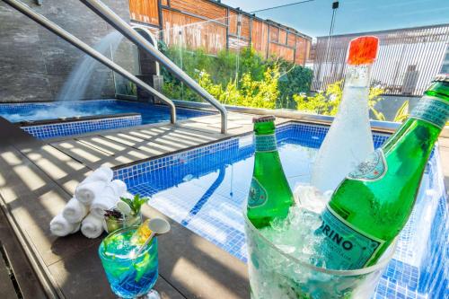 two bottles of alcohol sitting on a table next to a swimming pool at The Fives Downtown Hotel & Residences, Curio Collection by Hilton in Playa del Carmen