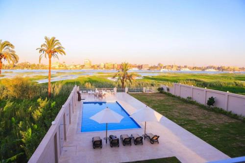 una vista aérea de una piscina con sillas y sombrilla en Royal Nile Villas - Nile View Apartment 1, en Luxor