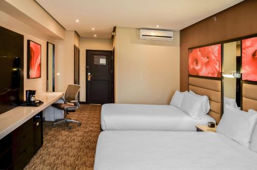 a hotel room with two beds and a desk at Hilton Garden Inn Guatemala City in Guatemala