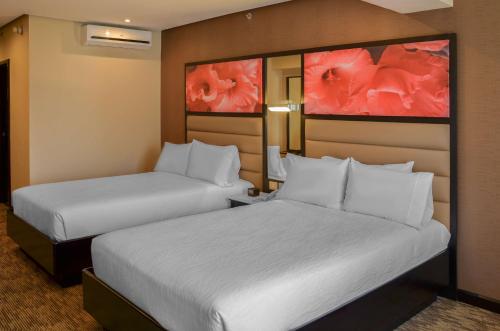 two beds in a hotel room with white sheets at Hilton Garden Inn Guatemala City in Guatemala