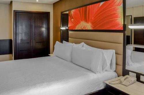a bedroom with a white bed and a telephone at Hilton Garden Inn Guatemala City in Guatemala
