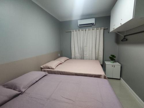 two beds in a small room with a window at Casas no Condomínio Dunas Residence - Santo Amaro do MA in Santo Amaro