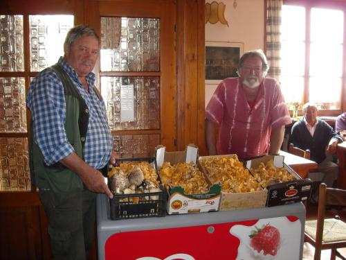 two older men standing next to a table of food at Al Tajol in Lamon