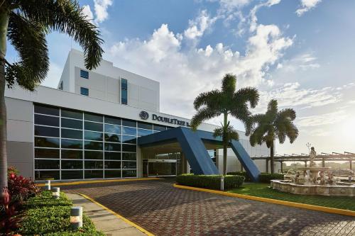 ein Gebäude mit Palmen davor in der Unterkunft DoubleTree by Hilton Managua in Managua