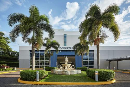 a building with palm trees in front of a fountain at DoubleTree by Hilton Managua in Managua