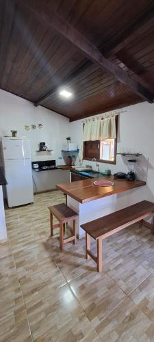 a kitchen with two benches and a table and a refrigerator at Porto do Sol - Chalé 07 in Pipa