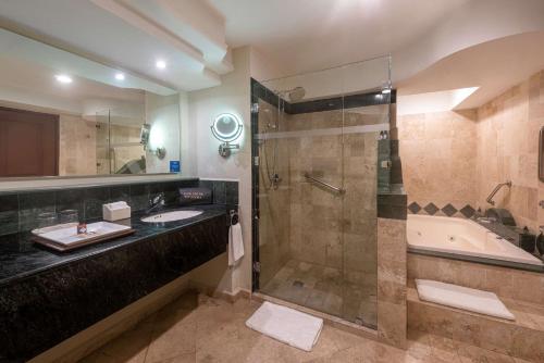 a bathroom with a shower and a sink and a tub at Villa Mercedes Curio Collection By Hilton in Mérida