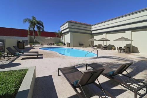 une piscine avec des chaises et des tables ainsi qu'un bâtiment dans l'établissement Hampton Inn Monterrey-Airport, à Monterrey
