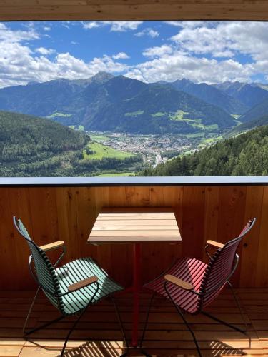 two chairs and a table on a deck with a view at Schallerhof Sterzing - Deine Auszeit mit Ausblick in unseren Ferienwohnungen auf dem Bergbauernhof in Südtirol in Vipiteno