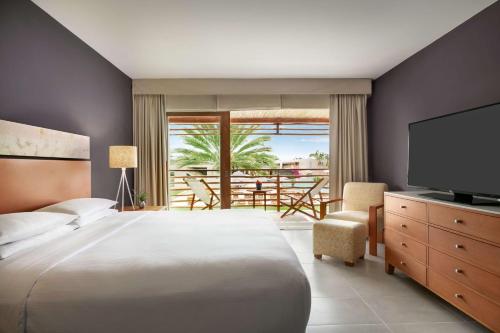 1 dormitorio con cama, TV y balcón en The Legend Paracas Resort, en Paracas