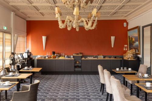 Un comedor con mesas y sillas y una cocina. en Hostellerie de la Renaissance, en Argentan