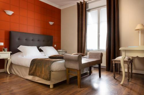 ein Schlafzimmer mit einem Bett, einem Schreibtisch und einem Stuhl in der Unterkunft Demeures & Châteaux Hostellerie de la Renaissance in Argentan