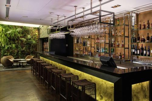 een bar met bruine krukken en flessen alcohol bij DoubleTree by Hilton Santiago - Vitacura in Santiago