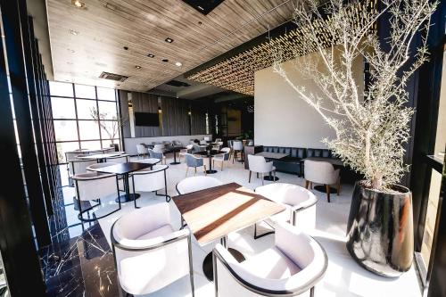 un restaurante con sillas blancas, una mesa y un jarrón en Hilton Garden Inn Santiago Del Estero - 4 Estrellas en Santiago del Estero