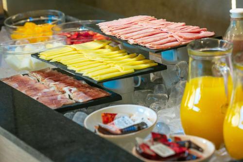 Un buffet de comida con carnes, quesos y jugo de naranja. en Hilton Garden Inn Santiago Del Estero - HILTON HOTELS, en Santiago del Estero