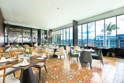 a restaurant with tables and chairs and large windows at Gran Hotel Costa Rica, Curio Collection By Hilton in San José