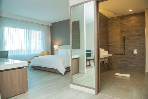 een slaapkamer met een bed en een badkamer met een douche bij Hilton Garden Inn Santa Ana, San Jose in San José