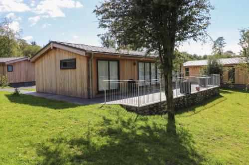 a log cabin with a deck and a tree at Hawthorn Croft in Ulverston