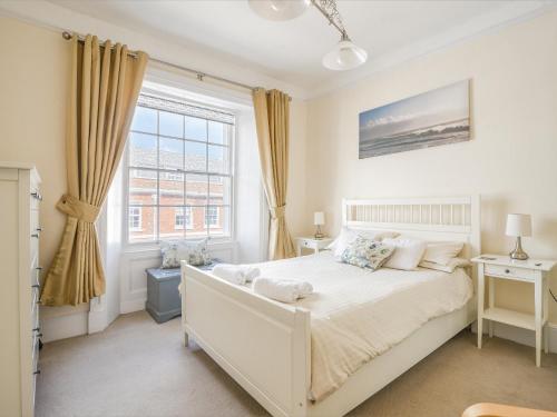 een slaapkamer met een wit bed en een raam bij Sublyme in Lyme Regis