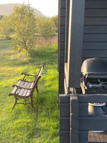 a bench sitting next to a grill on a house at Log house with a view - Bjalki in Hella