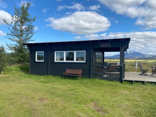 ein schwarzes winziges Haus mit einer Bank im Gras in der Unterkunft Log house with a view - Bjalki in Hella