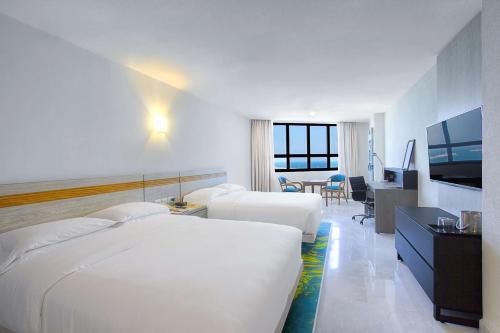 een hotelkamer met 2 bedden en een televisie bij DoubleTree by Hilton Veracruz in Veracruz