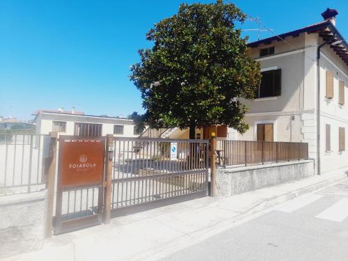 a fence in front of a white building with a tree at Foiarola in Begliano