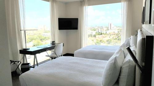 a hotel room with two beds and a desk and a window at Hampton by Hilton Santa Cruz in Santa Cruz de la Sierra