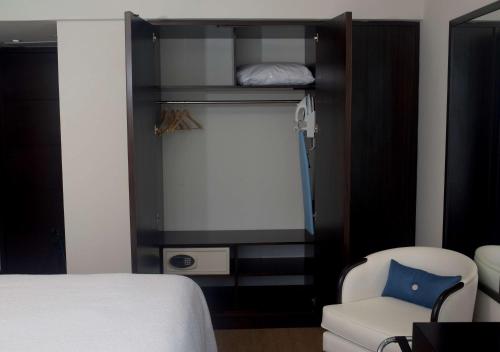 a bedroom with a bed and a chair and a window at Hampton by Hilton Santa Cruz in Santa Cruz de la Sierra