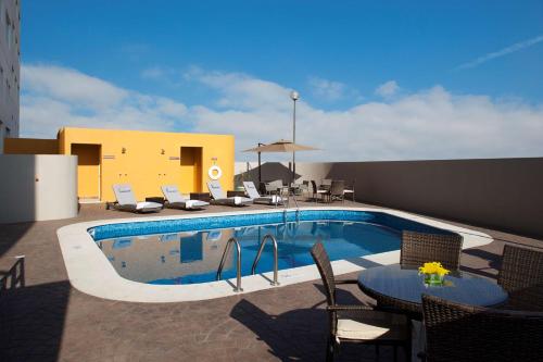 una piscina con sillas y una mesa junto a un edificio en Hampton Inn by Hilton Silao-Aeropuerto, Mexico, en Silao