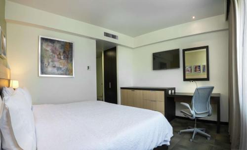 a bedroom with a bed and a desk and a computer at Hampton Inn by Hilton Silao-Aeropuerto, Mexico in Silao