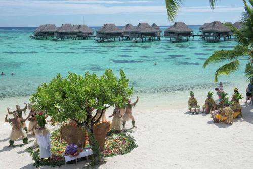 a group of people on a beach with the ocean at Hilton Moorea Lagoon Resort & Spa in Papetoai
