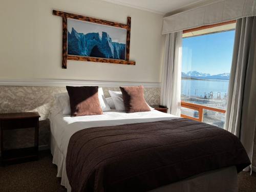 a bedroom with a bed with a view of the ocean at Darwin Hotel in Puerto Natales