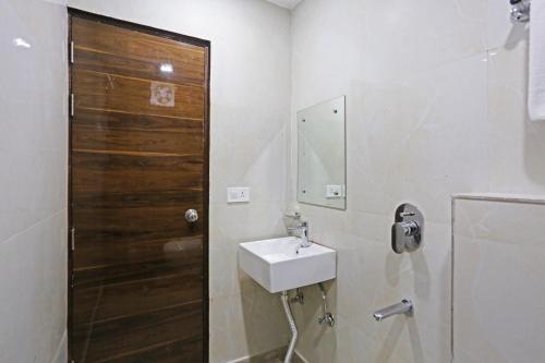 a bathroom with a sink and a wooden door at Hotel Vijaydeep Palace Near Delhi Airport in New Delhi