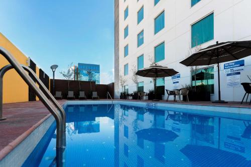a swimming pool with chairs and umbrellas next to a building at Hampton Inn by Hilton Leon in León
