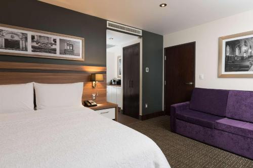a hotel room with a bed and a purple couch at Hampton Inn by Hilton Leon in León