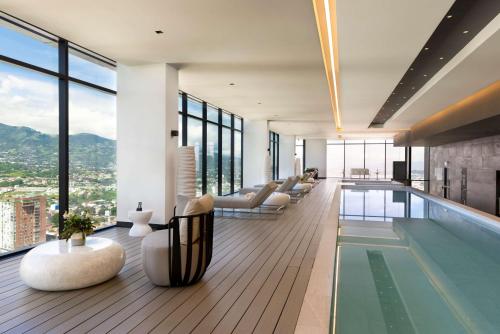 uma sala de estar com piscina e janelas em Hilton San Jose La Sabana em San José
